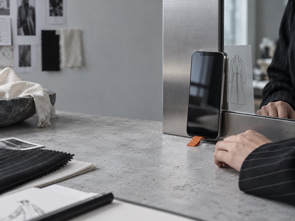 A phone, garment sketch, and fabric samples in a fashion studio